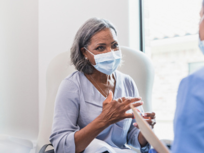 Indian woman with gray hair sitting in doctor's office talking with hands